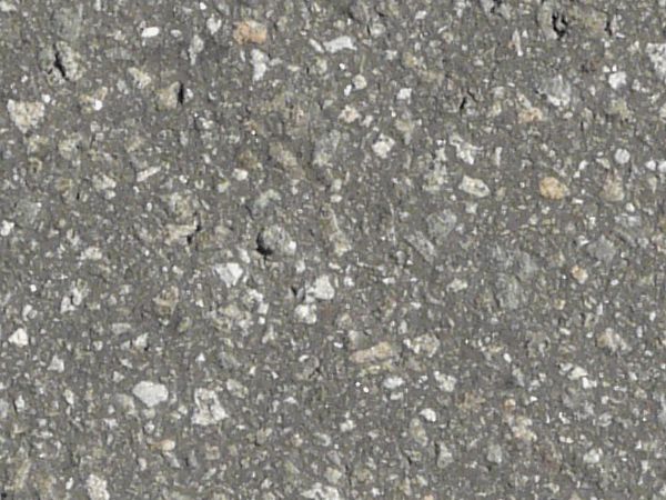 Rough asphalt surface in dark grey tone with embedded stones throughout.
